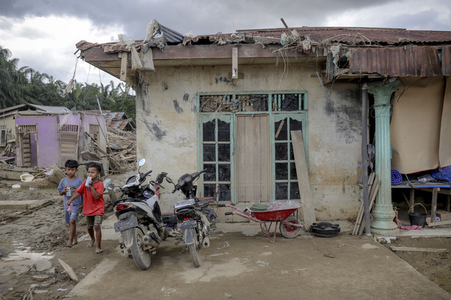 Dua bocah berjalan didekat rumah yang hancur akibat banjir bandang di Desa Kota Lintang Bawah, Kecamatan Kuala Simpang, Kabupaten Aceh Tamiang, Aceh, Senin (22/12/2025). Foto: Jamal Ramadhan/kumparan