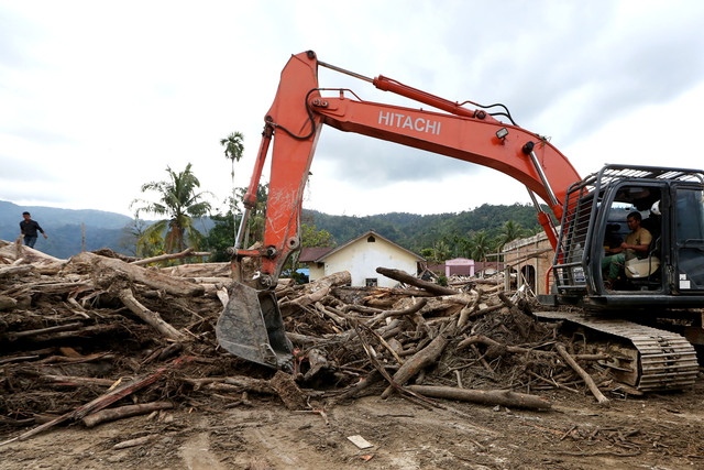 Petugas mengoperasikan alat berat untuk mengangkut lumpur dan kayu gelondongan yang menghalangi badan jalan lintas penghubung Kabupaten Aceh Timur dengan Kabuopaten Gayo Lues di Lokop, Serbajadi, Aceh Timur, Aceh, Senin (22/12/2025). Foto: ANTARA FOTO/Irwansyah Putra