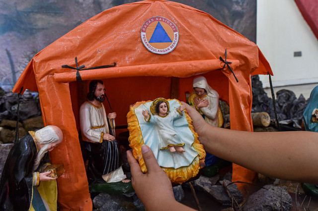 Umat Kristiani merapikan patung bayi Yesus di diorama tempat kelahiran Yesus, Gereja Katolik Santo Thomas, Desa Pandan Makmur, Tanjung Jabung Timur, Jambi, Selasa (23/12/2025). Foto: Wahdi Septiawan/ANTARA FOTO