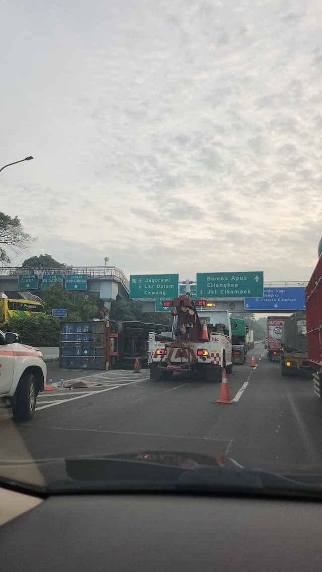 Sebuah truk kontainer terguling di ruas Tol JORR tepatnya di KM 32, persimpangan dari arah Pasar Minggu menuju Bogor dan Bekasi, Kamis (25/12). Foto: Aditia Noviansyah/kumparan