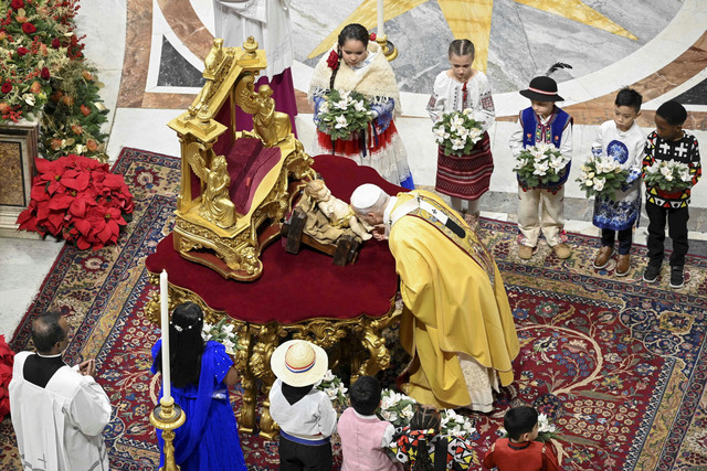 Paus Leo XIV mencium bayi Yesus saat Misa Malam Natal di Basilika Santo Petrus, Vatikan, Rabu (24/12/2025). Foto: Vatican Media/Handout via REUTERS
