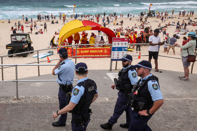 Petugas polisi berpatroli di dekat pengunjung pantai pada Hari Natal di Pantai Bondi di Sydney, Australia, Kamis (25/12/2025). Foto: David Gray/AFP