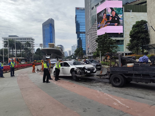 Petugas evakusi mobil yang menabrak separator jalan di kawasan Bundaran HI, Jakarta pada Kamis (1/1/2026). Foto: Luthfi Humam/kumparan