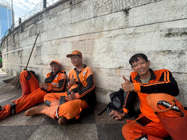 Jaeni, Listyo, dan Dahlan (50), petugas Penanganan Prasarana dan Sarana Umum di sela tugas membersihkan sampah sisa perayaan tahun baru di Bundaran HI, Jakarta Pusat, Kamis (1/1). Foto: Amira Nada Fauziyyah/kumparan