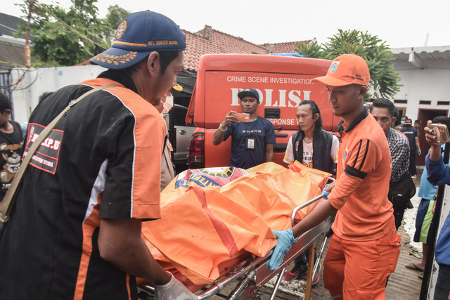 Relawan bersama petugas Penanganan Prasarana dan Sarana Umum (PPSU) memindahkan jenazah korban diduga keracunan ke mobil ambulance di Warakas VIII, Jakarta Utara, Jumat (2/1/2026). Foto: Fakhri Hermansyah/ANTARA FOTO