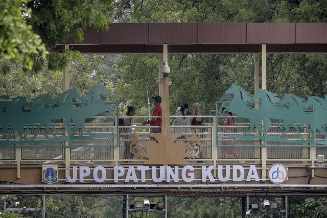 Sejumlah warga melewati Jembatan Penyebrangan Orang (JPO) Patung Kuda di Jalan Medan Merdeka Barat, Jakarta Pusat, Sabtu (3/1/2026). Foto: Jamal Ramadhan/kumparan