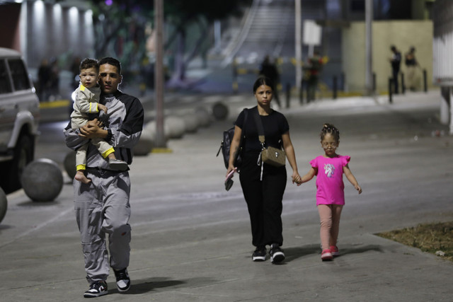 Sejumlah warga berjalan untuk mengungsi setelah ledakan dan pesawat terbang rendah saat serangan udara yang diduga dari Amerika Serikat di Caracas, Venezuela, Sabtu (3/1/2026). Foto: Cristian Hernandez/AP Photo