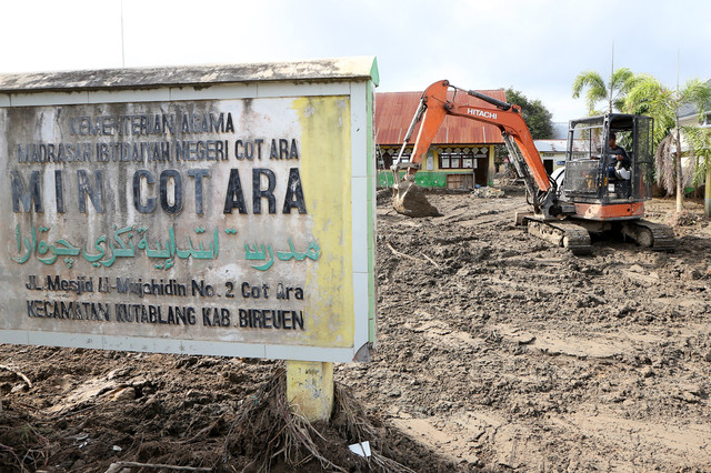 Alat berat dioperasikan untuk membersihkan halaman sekolah dari timbunan lumpur pascabencana banjir bandang di MIN Cot Ara, Kuta Blang, Bireuen, Aceh, Minggu (4/1/2026). Foto: Irwansyah Putra/ANTARA FOTO