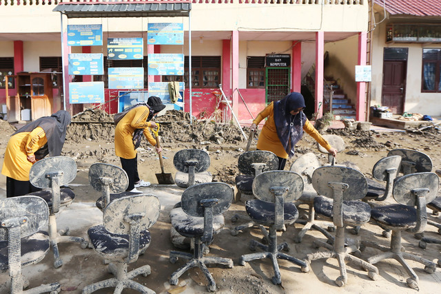 Tenaga pendidik membersihkan halaman dan beberapa kursi sekolah dari lumpur pascabanjir bandang di SD Negeri 3 Percontohan Peusangan, Bireuen, Aceh, Minggu (4/1/2026). Foto: Irwansyah Putra/ANTARA FOTO