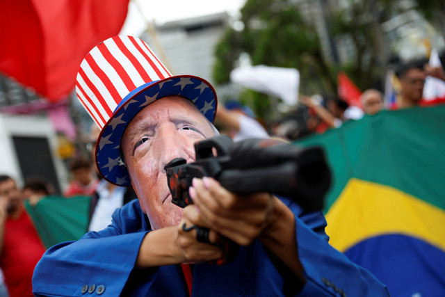 Seorang pria mengenakan topeng bergambar Presiden AS Donald Trump saat demonstrasi menentang serangan AS di Venezuela dan penangkapan Presiden Maduro, di Sao Paulo, Brasil, Senin (5/1/2026). Foto: TUANE FERNANDES/REUTERS