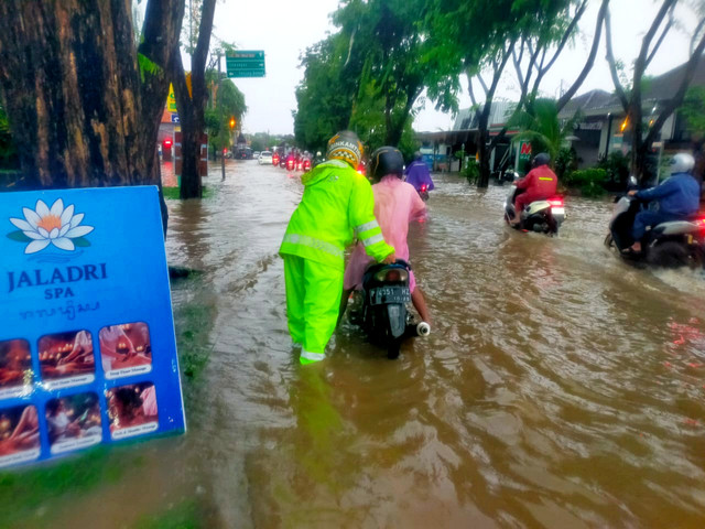 Polisi mendorong motor di jalanan yang tergenang air di kawasan Kuta Selatan, Badung, Bali, Kamis (8/1/2026). Foto: Dok. Polresta Denpasar