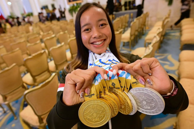 Atlet triathlon Martina Ayu Pratiwi menunjukkan medali yang diraih saat menyerahkan bonus kepada atlet peraih medali pada SEA Games Thailand di Istana Negara, Jakarta, Kamis (8/1/2025). Foto: Instagram/ @sekretariat.kabinet