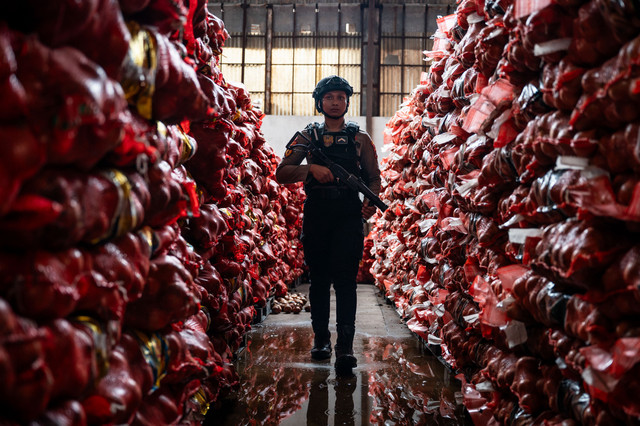 Polisi berjaga di samping barang bukti bawang bombai ilegal di Kompleks Pergudangan Bandarharjo, Semarang, Jawa Tengah, Sabtu (10/1/2026). Foto: Aprillio Akbar/ANTARA FOTO