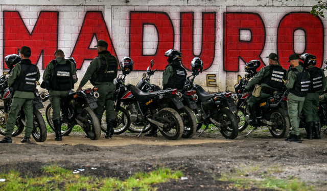 Anggota Garda Nasional berjaga di depan mural mantan Presiden Venezuela Nicolas Maduro di Caracas, Venezuela, Sabtu (10/1/2026). Foto: Juan BARRETO / AFP