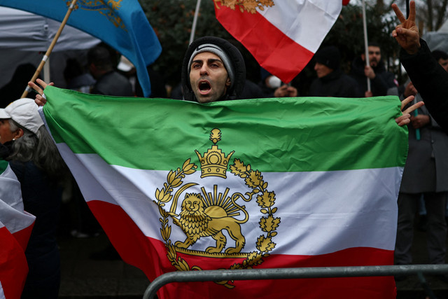 Demonstran anti-rezim Iran mengibarkan bendera Iran sebelum revolusi 1979 dengan lambang Singa dan Matahari di luar Kedutaan Besar Iran, London, Jumat (9/1/2026). Foto: HENRY NICHOLLS / AFP