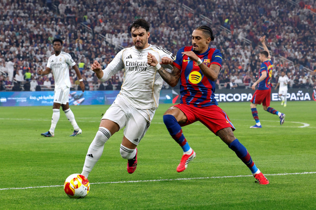 Duel Raul Asencio dan Raphinha dalam laga Barcelona vs Real Madrid saat Final Piala Super Spanyol 2026 di King Abdullah Sports City Stadium, Jeddah, Arab Saudi, pada Senin (12/1) dini hari WIB. Foto: REUTERS/Vincent West