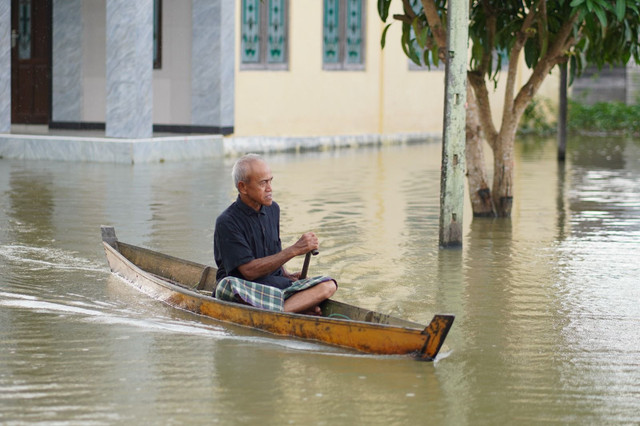 Warga Desa Keramat Baru menggunakan perahu untuk melintasi banjir pada Sabtu (10/1/2026). Foto: Dok. kumparan