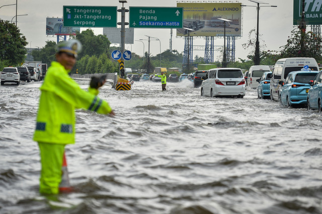 Polisi mengatur lalu lintas kendaraan saat banjir di Jalan Tol Sedyatmo, Kota Tangerang, Banten, Senin (12/1/2026). Foto: Putra M. Akbar/ANTARA FOTO