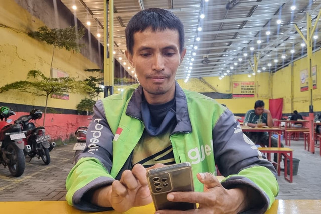 Driver ojek online di Surabaya, Ambar Wanto, yang belajar bahasa Inggris dan direkam saat menunggu orderan. Foto: Farusma Okta Verdian/kumparan