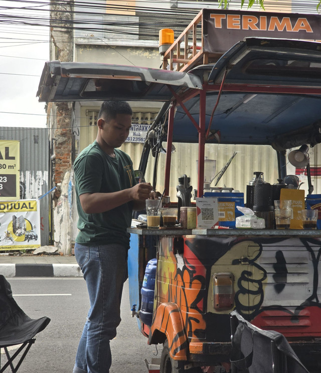Di atas bajaj nyentrik, tangan terampil meracik aroma. Barista jalanan ini tak sekadar menyeduh kopi, tapi menuang semangat. Tiap adukan adalah dedikasi, menghadirkan kenikmatan autentik nan hangat di tengah riuh kota yang tak pernah mati. Foto: Dok. Pribadi
