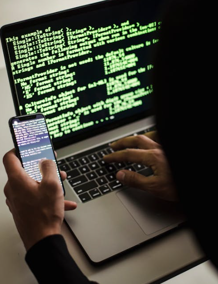 Sumber Foto: https://www.pexels.com/id-id/foto/peretas-yang-tidak-dapat-dikenali-dengan-ponsel-cerdas-yang-mengetik-di-laptop-di-meja-5935791/