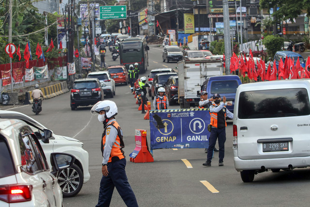 Petugas Sat Lantas Polres Bogor bersama petugas Dishub Kabupaten Bogor mengarahkan kendaraan wisatawan saat penyekatan kendaraan nomor polisi ganjil genap di jalur wisata Puncak, Gadog, Kabupaten Bogor, Jawa Barat, Jumat (16/1/2026). Foto: ANTARA FOTO/Yulius Satria Wijaya