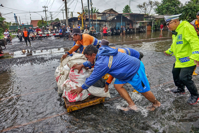 Petugas mendorong karung berisi batuan kricak (batuan kecil) yang akan digunakan sebagai konstruksi tambahan pada ruas rel kereta api yang terendam banjir di sekitar Stasiun Pekalongan, Kota Pekalongan, Jawa Tengah, Sabtu (17/1/2026). Foto: Harviyan Perdana Putra/ANTARA FOTO