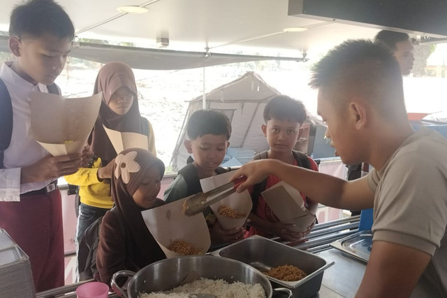 Personel Polri melayani lima siswa yang mengantre sambil membawa nasi dalam bungkusan terbuka di Kabupaten Aceh Tamiang, Aceh, Kamis (15/1/2026). Foto: Dok. Bakom RI