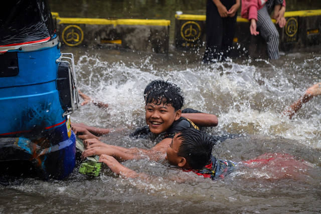 Anak-anak bermain air di tengah banjir di kawasan Gunung Sahari, Jakarta, Minggu (18/1/2026). Foto: Iqbal Firdaus/kumparan