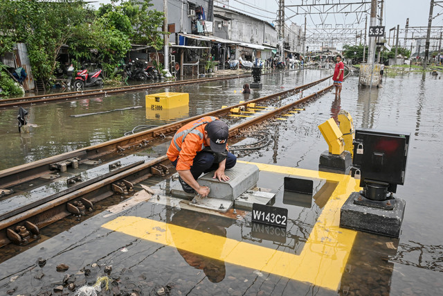Petugas melakukan pemeriksaan pada mesin wesel perlintasan kereta yang terendam banjir di kawasan Kampung Bandan, Jakarta, Minggu (18/1/2026). Foto: Sulthony Hasanuddin/ANTARA FOTO 