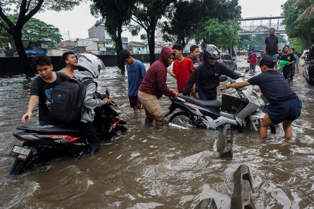 Warga membantu pengendara sepeda motor yang mogok saat menerobos banjir di Jalan Daan Mogot, Jakarta, Kamis (22/1/2026). Foto: Ika Maryani/ANTARA FOTO