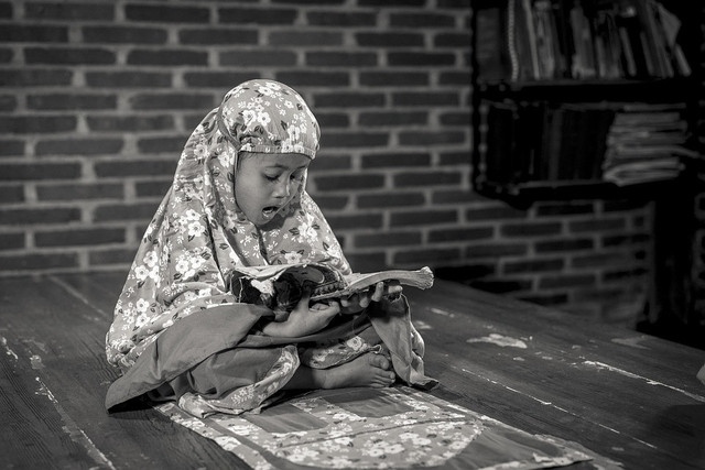 Seorang anak kecil membaca Al-Qur'an di rumah. Foto: Pixabay
