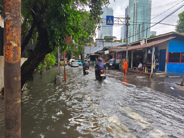 Sejumlah pengendara melintasi genangan air yang berangsur surut di kawasan Bendungan Hilir, Jakarta Pusat, Jumat (23/1). Foto: Jeni Ritanti/kumparan