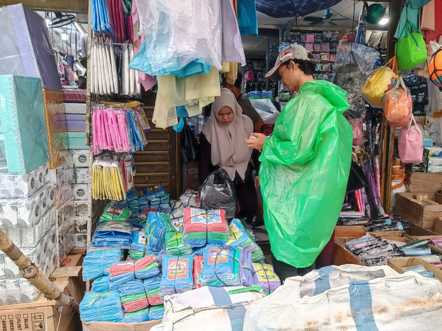 Pedagang payung dan jas hujan di Pasar Asemka mengaku saat ini permintaan terhadap jas hujan tinggi, Jumat (23/1).  Foto: Ryan Iqbal/kumparan