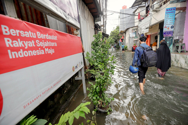 Warga berjalan melintasi banjir yang masih menggenangi permukiman warga RW 02, Kelurahan Rawa Buaya, Cengkareng, Jakarta Barat, Sabtu (24/1/2026). Foto: Jamal Ramadhan/kumparan