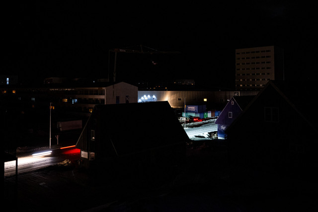Sebuah jalan  diterangi oleh lampu depan mobil selama pemadaman listrik di pusat kota Nuuk, Greenland, Sabtu (24/1/2026). Foto: Jonathan NACKSTRAND / AFP