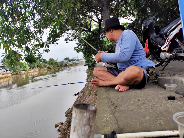 Warga memancing di pinggiran Kali Angke, Rawa Buaya, Jakarta Barat, Minggu (25/1/2026). Foto: Luthfi Humam/kumparan