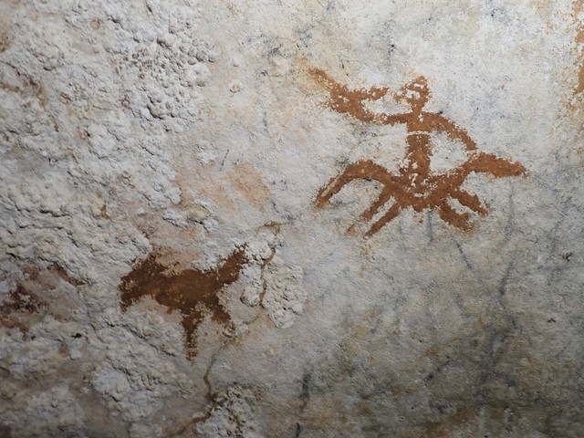 Lukisan gua berupa sosok manusia dan burung dengan jejak tangan yang memudar di antara keduanya di gua di Sulawesi. Foto: Maxime Aubert via AP