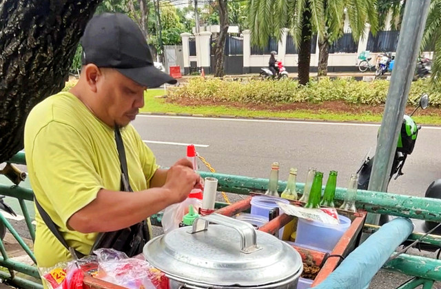 Tukang bubur racing, Jamal tengah menyajikan bubur di lapak dagangannya di Jakarta Pusat, Senin (26/1/2026). Foto: Widya/kumparan