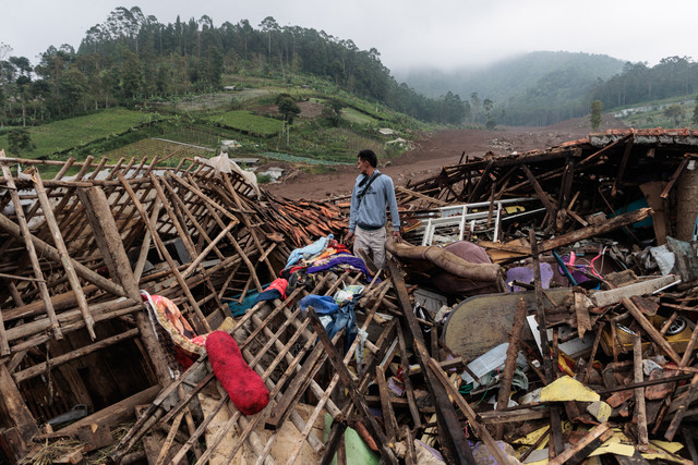 Seorang pria berdiri di dekat reruntuhan rumah saat tim penyelamat mencari korban yang terkubur longsor di desa Pasirlangu, Cisarua, Bandung, Jawa Barat, pada 26 Januari 2026. Foto: ADITYA AJI / AFP