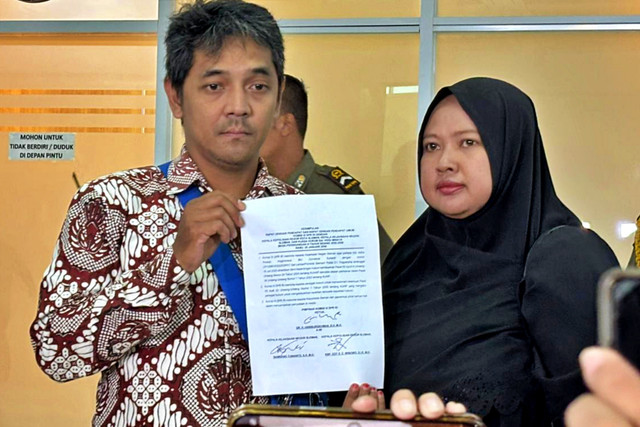 Hogi Miyana dan istrinya, Arsita Miyana memegang berkas kesimpulan rapat Komisi III soal kasus yang menimpa Hogi, yakni mengejar jambret berujung jadi tersangka di Kompleks Parlemen, Senayan, Jakarta Pusat, Rabu (28/1/2026). Foto: Abid Raihan/kumparan