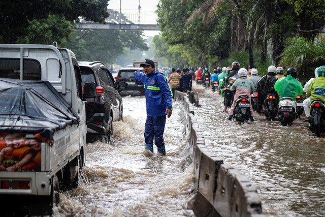 Petugas Suku Dinas Sumber Daya Air Jakarta Barat melakukan pengaturan lalu lintas akibat banjir yang merendam ruas Jalan Daan Mogot, Jakarta Barat, Kamis (29/1/2026). Foto: Iqbal Firdaus/kumparan