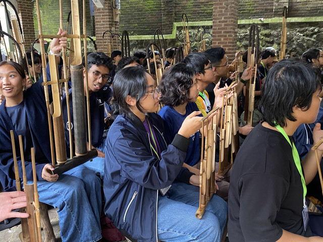 Siswa studi tur dari sekolah internasional Singapura tampak fokus mempraktikkan permainan angklung di Kampung Adat Cirendeu, Cimahi. (Dok. Penulis)