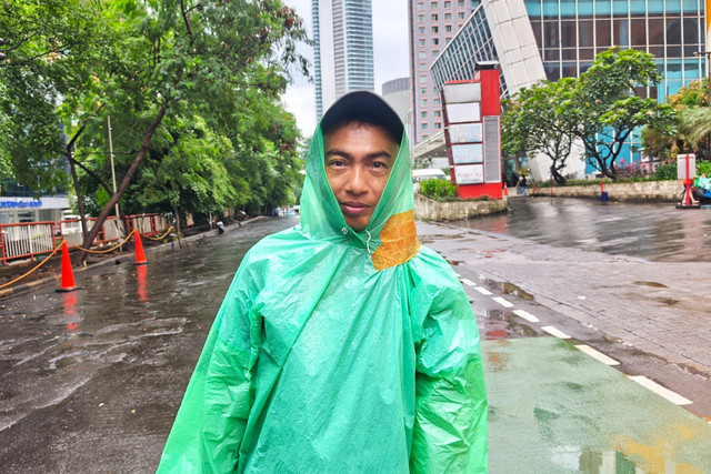 Adi (39), pedagang jas hujan keliling, saat ditemui di sekitar kawasan Bundaran HI, Jakarta Pusat, Minggu (1/2/2026). Foto: Jeni Ritanti/kumparan