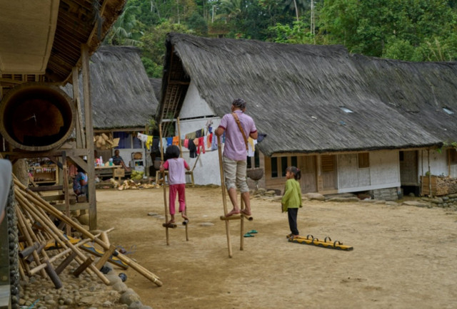 Anak-anak dan seorang pria sedang bermain egrang. Sumber foto: pexels.com