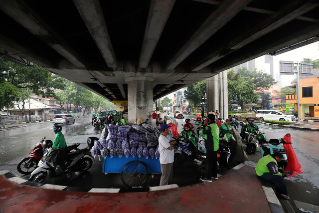 Pengendara sepeda motor berteduh akibat hujan lebat disertai angin kencang di bawah flyover Tendean, Jakarta Selatan, Rabu (4/2/2026). Foto: Jamal Ramadhan/kumparan