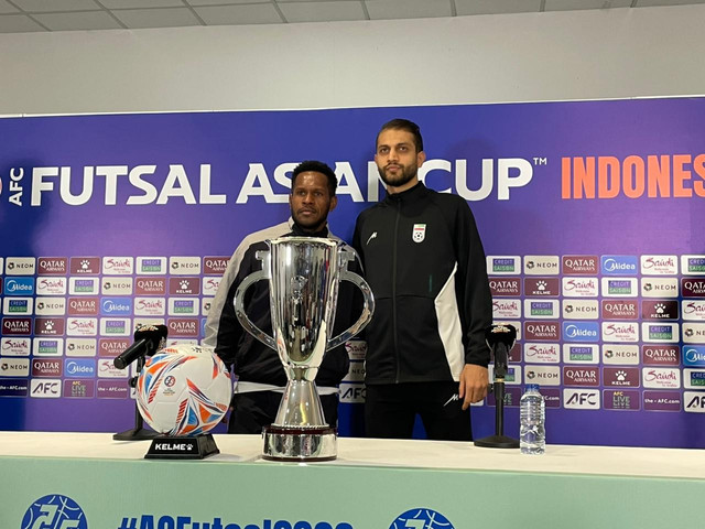 Pemain Timnas Futsal Indonesia, Wendy Brian Ick; dan pemain Iran, Mohammad Hossein Derakhshani; berpose dengan trofi Piala Asia 2026. Foto: Aji Nugrahanto/kumparan