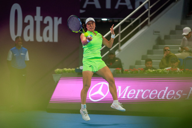 Janice Tjen dari Indonesia memukul bola balasan melawan Iga Swiatek dari Polandia selama pertandingan tunggal putri mereka di turnamen tenis Qatar Open di Doha, Selasa (10/2/2026). Foto: Karim Jaafar/AFP