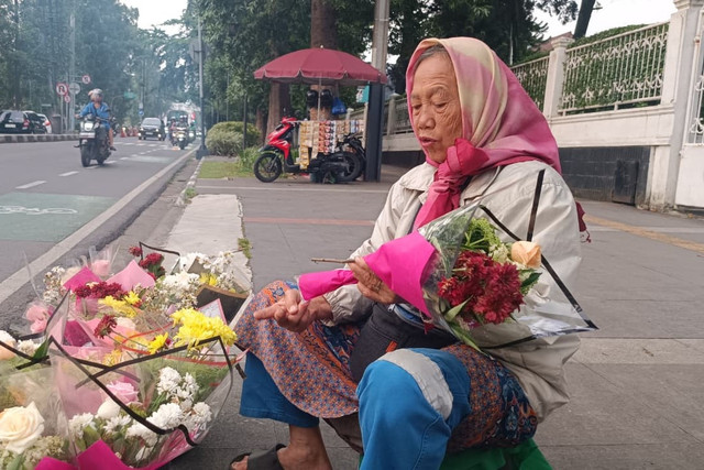 Euis, penjual bucket bunga di Jalan Ir. H. Juanda, Dago, Bandung, Minggu (15/2/2026). Foto: Abisatya Ramdhani/kumparan