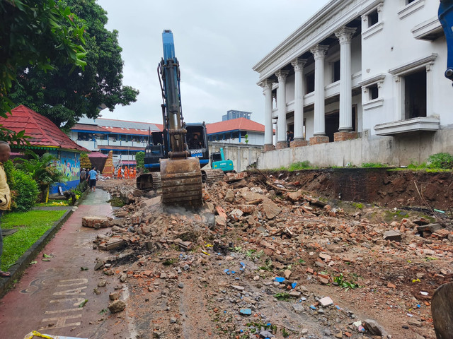 Petugas gunakan alat berat memperbaiki area yang terdampak dari robohnya bangunan tembok rumah di sebelah SMP Negeri 182 Jakarta, Kalibata Jakarta Selatan, Senin (16/2/2026). Foto: Jeni Ritanti/kumparan